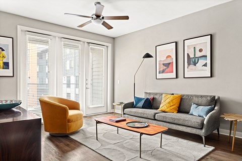 a living room with a couch and a chair and a ceiling fan